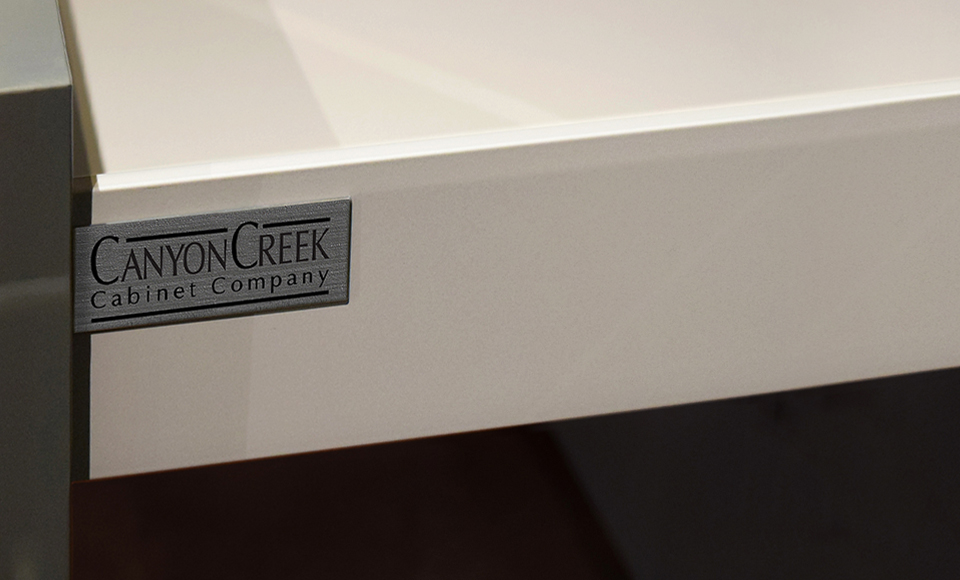 Canyon Creek Cabinet Company Logo Affixed to a Millennia Collection Light Grey Metal Drawer | Canyon Creek Cabinet Company