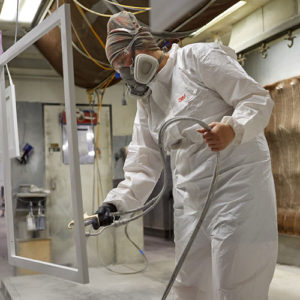 Canyon Creek Employee in a Hazmat Suit Painting a Kitchen Cabinet | Canyon Creek Cabinet Company